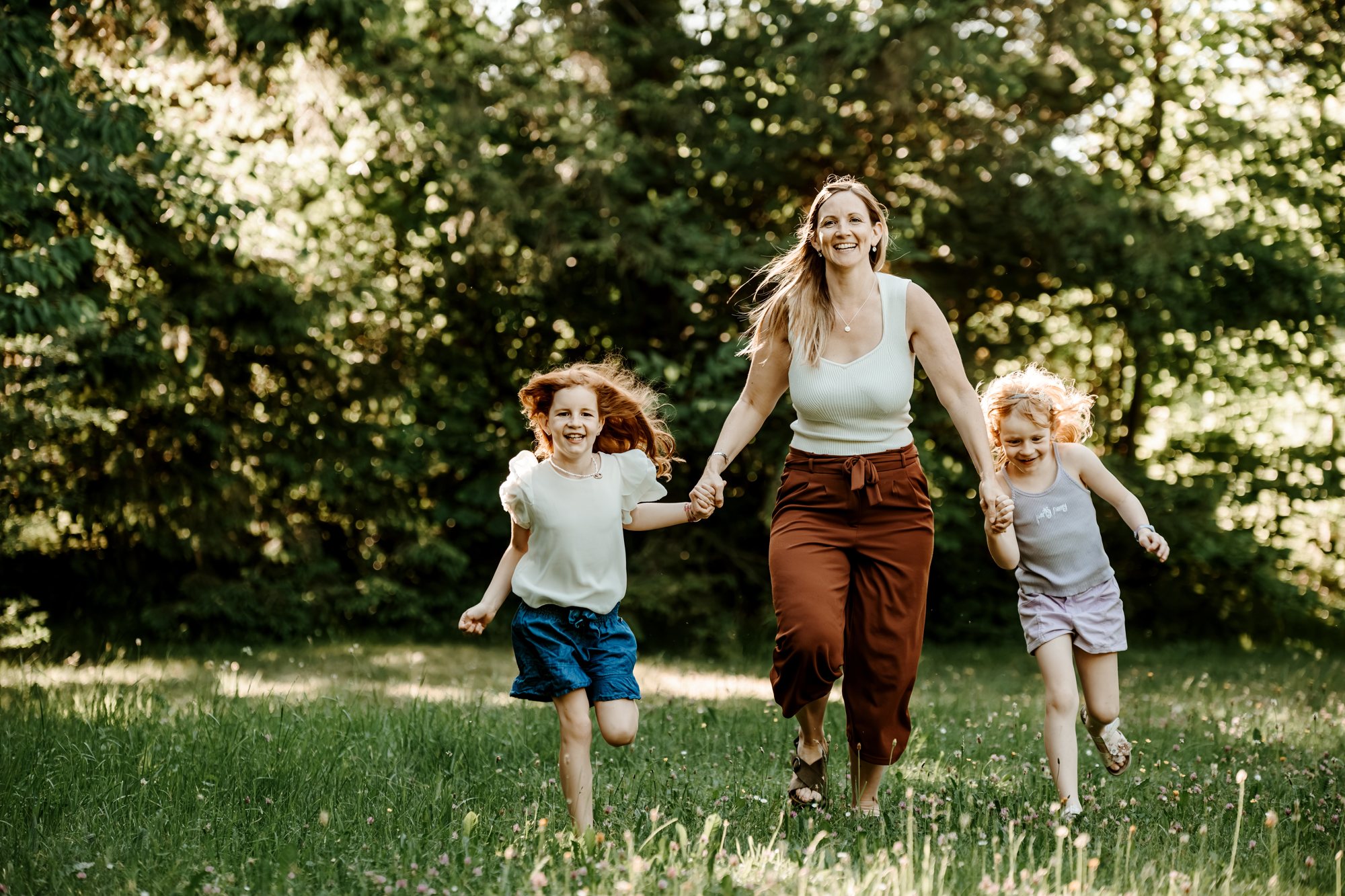 Familie rennt lachend über eine Wiese