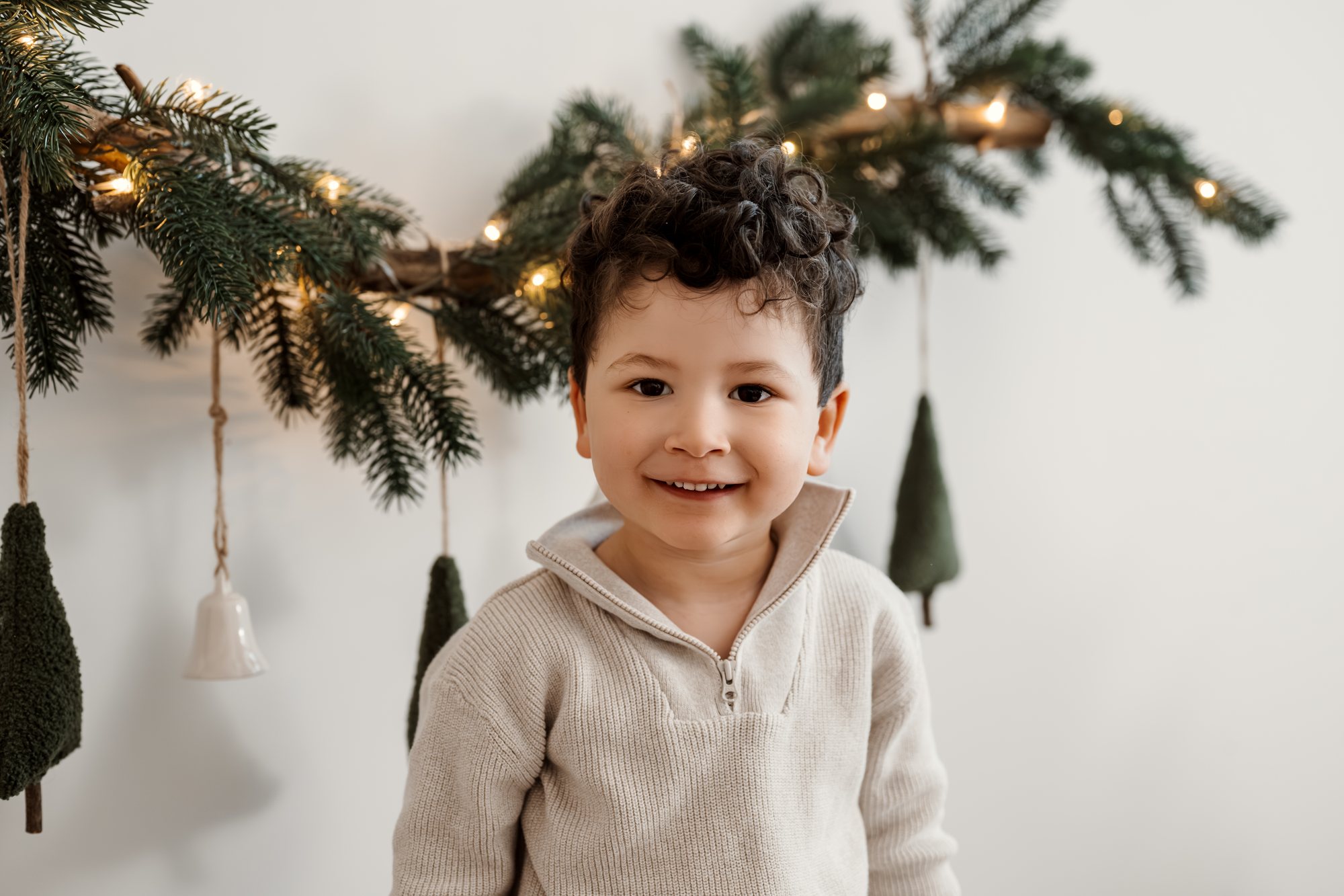 Mädchen im cremefarbenen Pullover vor dem Weihnachtsbaum